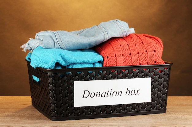 Donation box with clothing on brown background closeup