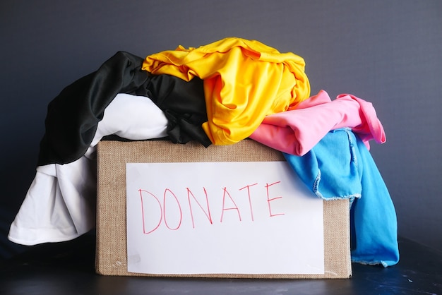 Donation box with donation clothes on a wooden table