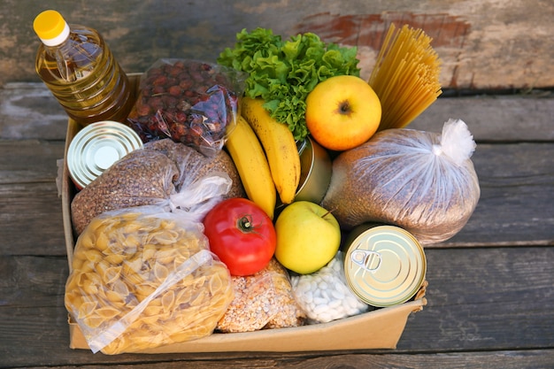 Donation box with food on old wooden background