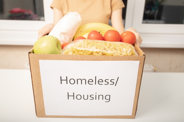 Donation and charity for the homeless. Women's hands holding a box of food products