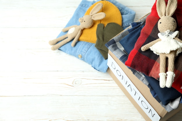 Donation concept with clothes on white wooden background