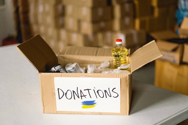 Donation food for refugees from Ukraine support of war victims helping people charity a box with the Ukrainian flagHumanitarian aid concept