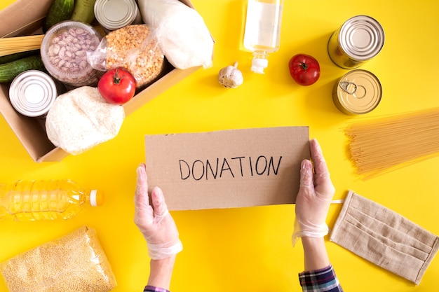 Donation. Food supplies crisis food stock for quarantine isolation period on yellow background. Rice, peas, cereals, canned food, oil, vegetables, mask, sanitizer. Food delivery, coronavirus.