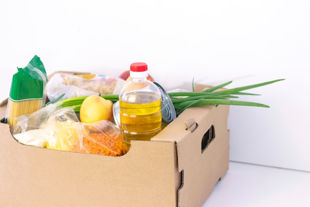 Donation. grocery box, help products to those in need. donation box. cardboard box with food essentials on a white surface.