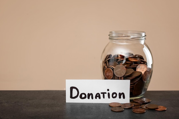 Photo donation jar and coins on table against color background space for text