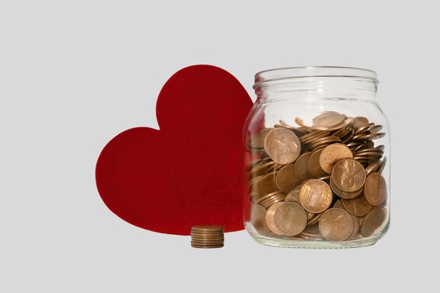 Donation Jar with Coins and Red Heart on Table