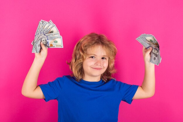 Photo donation saving charity and finance concept kid showing money dollar bills standing dreamy of rich against isolated studio background