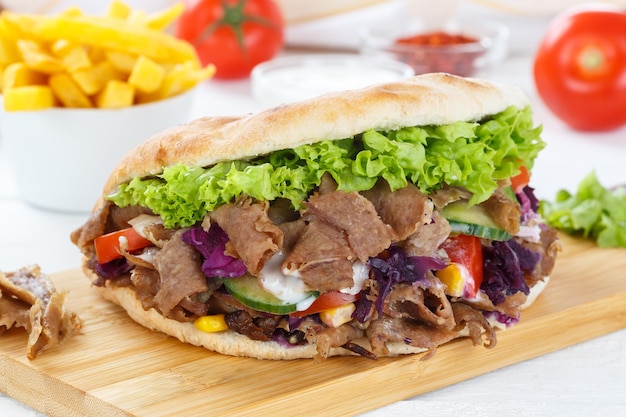 Doner kebab doner kebap fastfood maaltijd in flatbread met frietjes op een houten bord