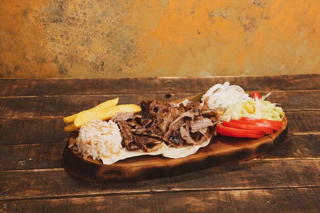 Doner kebab ligt op de snijplank Shoarma met vleesuiensalade ligt op een donker oud hout