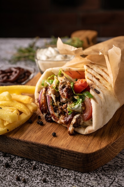 Doner kebab a shawarma in a pit of fresh vegetables and meat with large spices restaurant serving on...