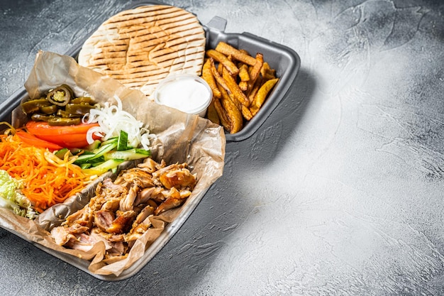 Doner kebab Shawarma on a plate with french fries and salad in box to go take away White background Top view Copy space