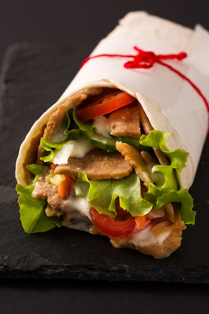 Doner kebab or shawarma sandwich on black slate Close up