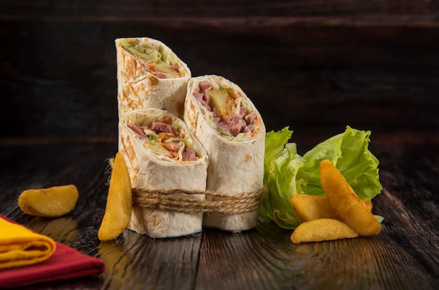 Doner kebab, shawarma with rustic potatoes and cabbage on a wooden textured background