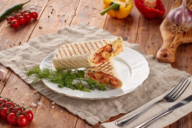 Doner kebab with meat, vegetables and sauce, wooden background