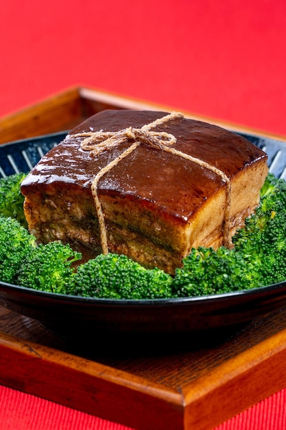 Dong Po Rou Dongpo pork meat in a beautiful blue plate with green broccoli vegetable traditional festive food for Chinese new year cuisine meal close up