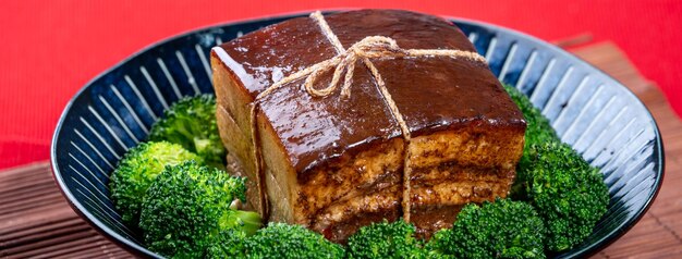 Dong Po Rou Dongpo pork meat in a beautiful blue plate with green broccoli vegetable traditional festive food for Chinese new year cuisine meal close up