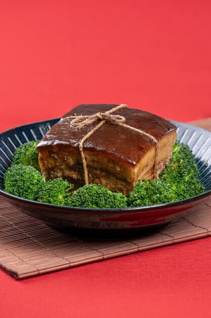 Dong Po Rou Dongpo pork meat in a beautiful blue plate with green broccoli vegetable traditional festive food for Chinese new year cuisine meal close up