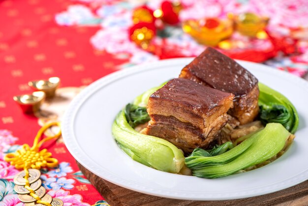 Dong Po Rou (Dongpo pork meat) in a beautiful blue plate with green broccoli vegetable, traditional festive food for Chinese new year cuisine meal, close up.