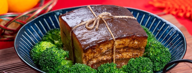 Dong po rou dongpo pork meat in a beautiful blue plate with\
green broccoli vegetable traditional festive food for chinese new\
year cuisine meal close up