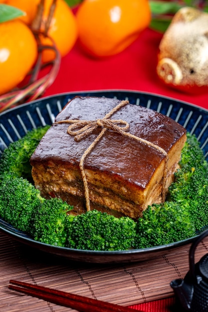 Dong Po Rou Dongpo pork meat in a beautiful blue plate with green broccoli vegetable traditional festive food for Chinese new year cuisine meal close up