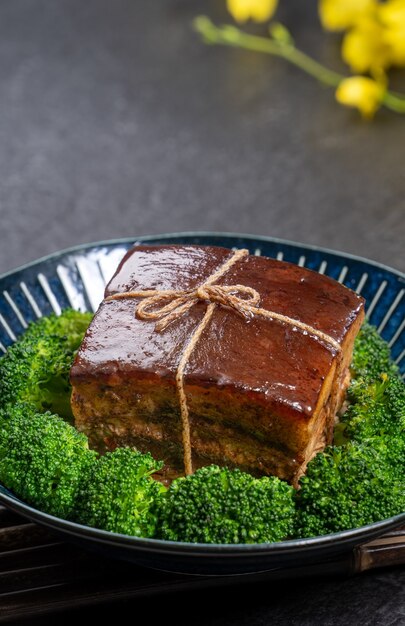 Dong Po Rou (Dongpo-varkensvlees) in een mooie blauwe plaat met groene broccoligroente, traditioneel feestelijk voedsel