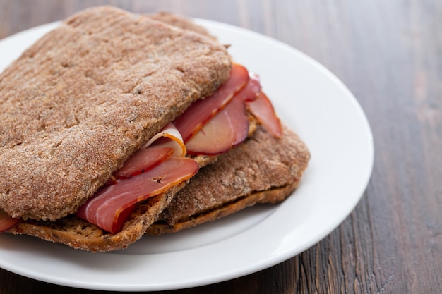 Donker brood met gerookt vlees op witte plaat