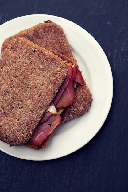 Donker brood met gerookt vlees op witte plaat