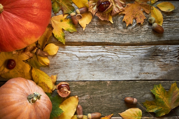 donker houten oppervlak met pompoenen, verdorde bladeren, eikels en kastanjes, thanksgiving achtergrond