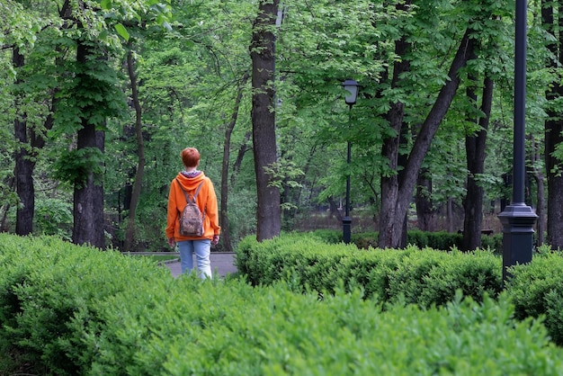 Donker park met groene gebladerte rijstroken omheind met dichte struiken en eenzame vrouw Vladikavkaz Rusland