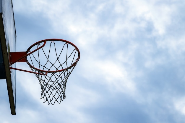 Donker silhouet van de hoepel van het straatbasketbal een bewolkte dag.