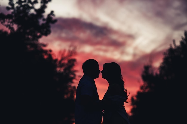 Donker silhouet van jongen en meisje tegen prachtige zonsondergang.