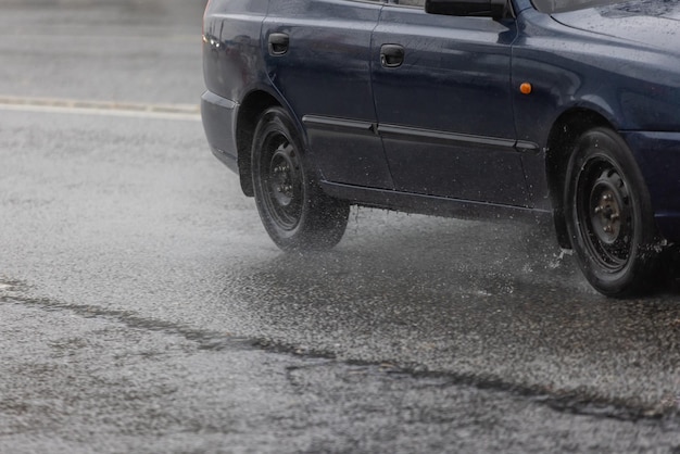 Donkerblauwe budgetauto die zich op regenachtige dag op asfaltweg beweegt