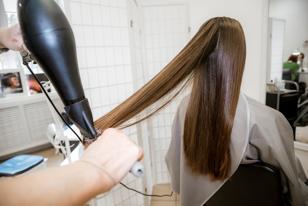 Donkerbruin meisje in een schoonheidssalon, haarverzorging. Kapsel, haarverven en wassen voor vrouwen bij de kapper.