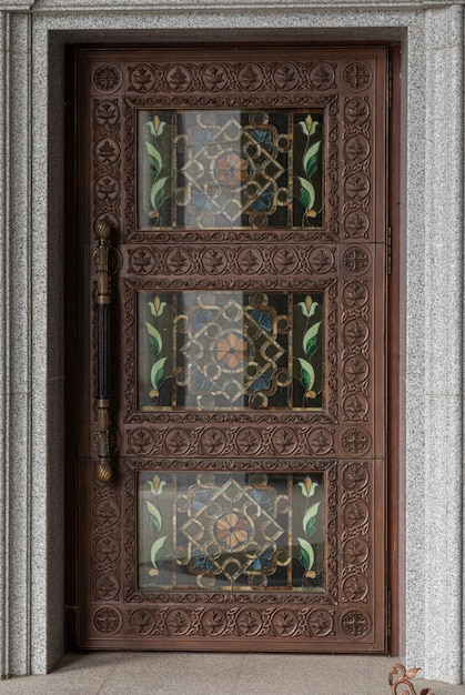 Donkerbruine houten deur met houtgravure en glas in lood