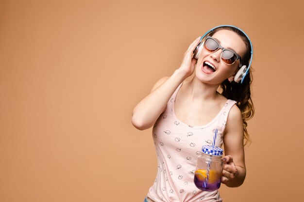 Donkerbruine jonge dame die en smakelijke limonade zingt drinkt