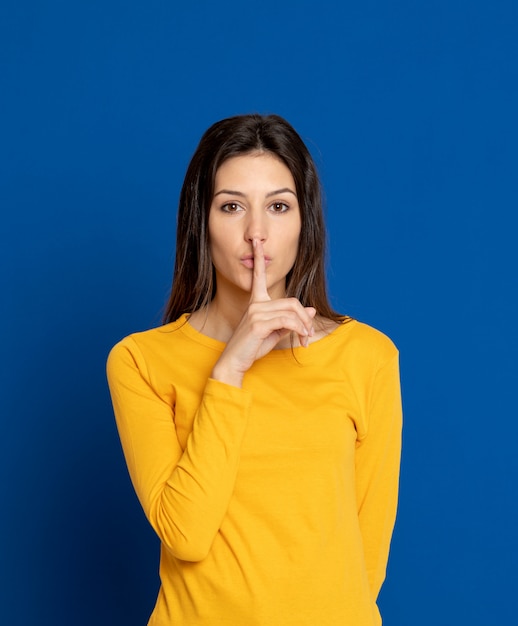 Donkerbruine jonge vrouw die over blauwe muur gesturing