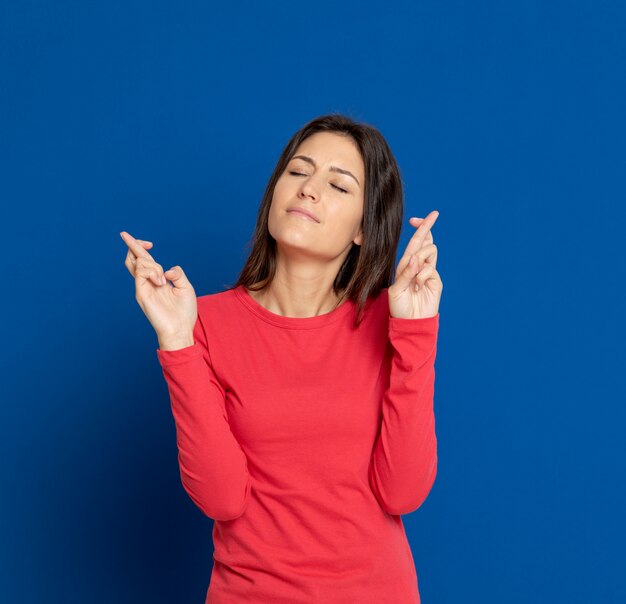 Donkerbruine jonge vrouw die over blauwe muur gesturing