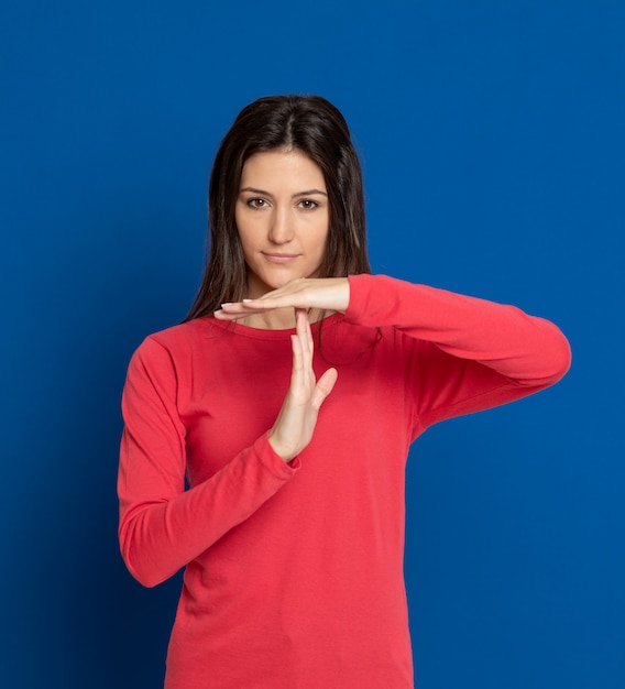 Donkerbruine jonge vrouw die over blauwe muur gesturing