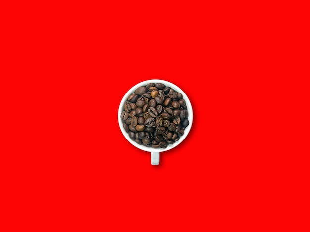 Donkerbruine koffiebonen in witte koffiekop en schotel op de middelste foto. Rode achtergrond.