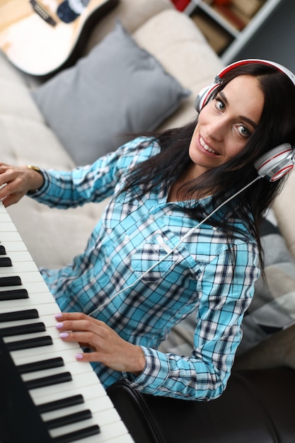 Donkerbruine vrouw die de piano met hoofdtelefoons speelt