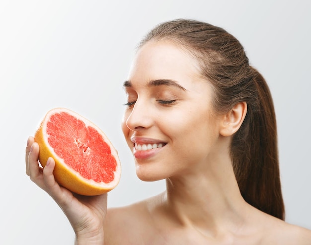 Donkerbruine vrouw die grapefruit met gesloten ogen snuift