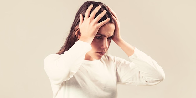 Donkerbruine vrouw die haar slapen aanraakt, voelt stress, op een grijze achtergrond. Vrouw die lijdt aan wanhopige hoofdpijn, gestrest vanwege pijn en migraine. Vrouw met harde hoofdpijn hand in hand op het hoofd