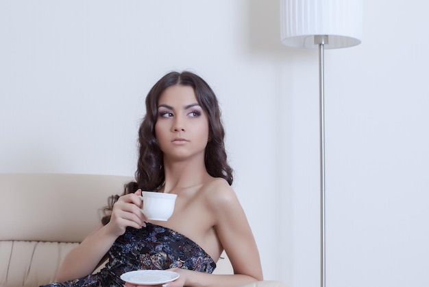 Donkerbruine vrouw die koffie drinkt in de woonkamer