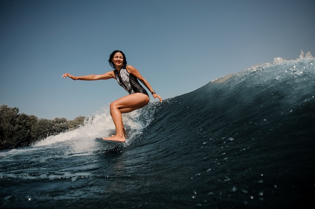 Donkerbruine vrouw die op een surfplank in overzees surft