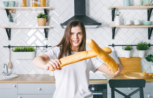 Donkerbruine vrouw die stokbrood als zwaarden zwaait in de moderne keuken