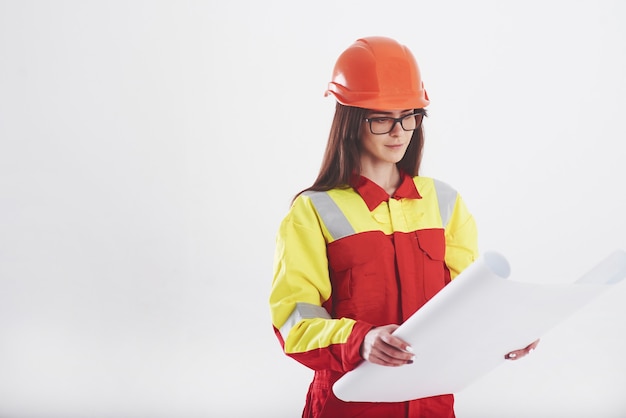 Donkerbruine vrouw in oranje en geel uniform staat tegen een witte muur in de studio