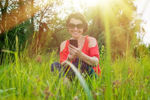 Donkerbruine vrouw met telefoon op het gras