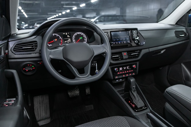 Donkere auto-interieur - stuurwiel, versnellingspook en dashboard, klimaatregeling, snelheidsmeter, display. Salon van een nieuwe stijlvolle auto