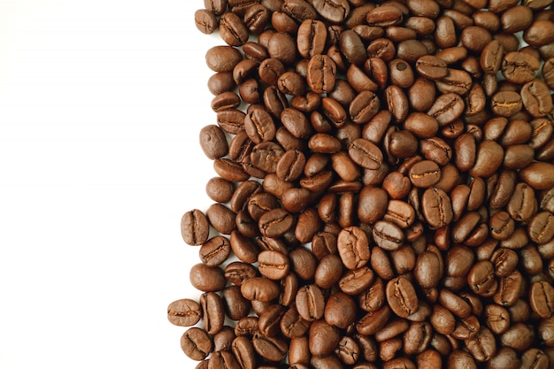 Donkere bruine geroosterde koffiebonen die op wit worden geïsoleerd