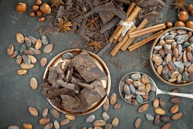 Donkere chocolade in een compositie met cacaobonen en noten, op een oude achtergrond.